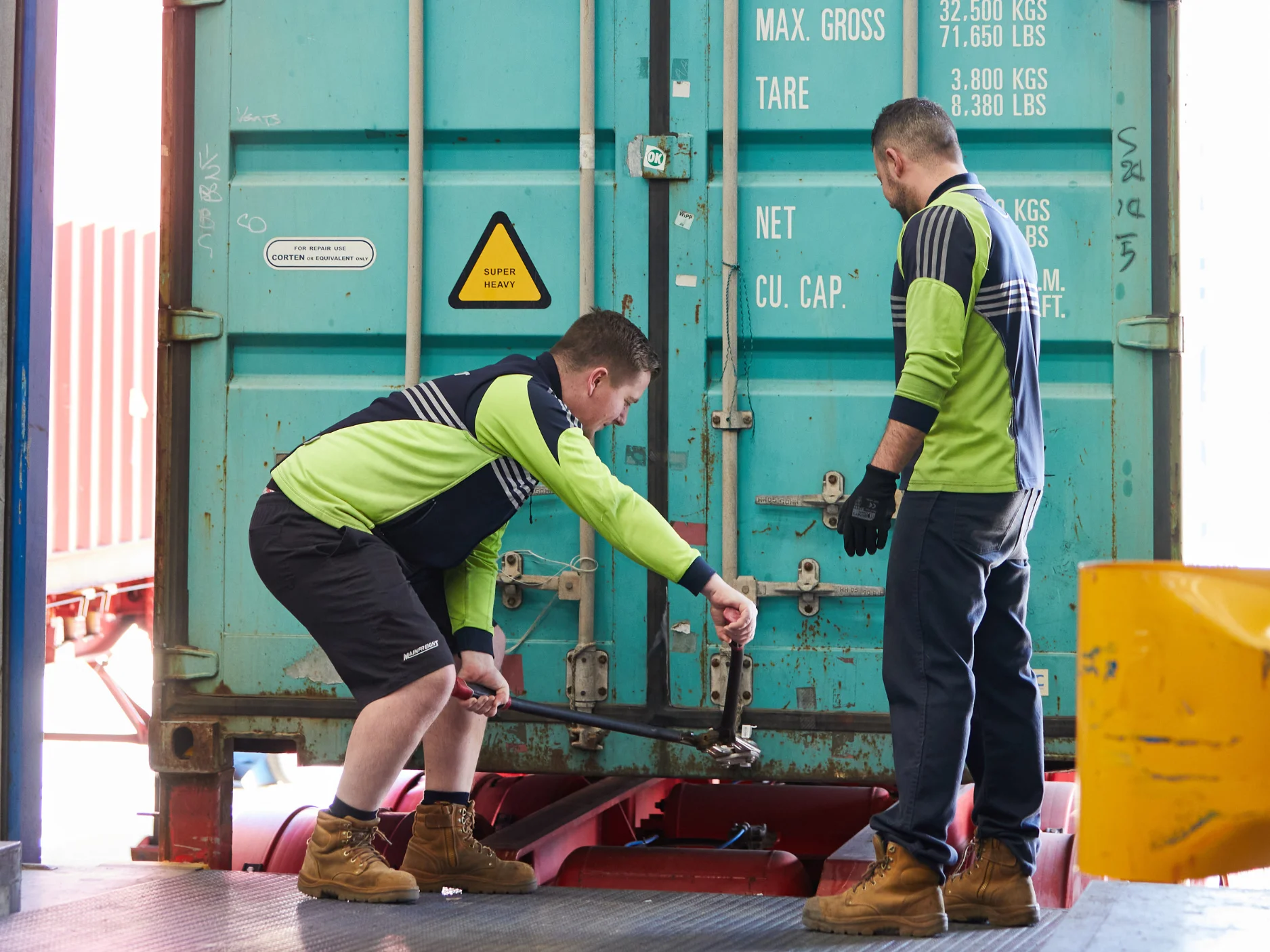 Two Mainfreight Team Members opening a shipping a container that has defence logistics freight