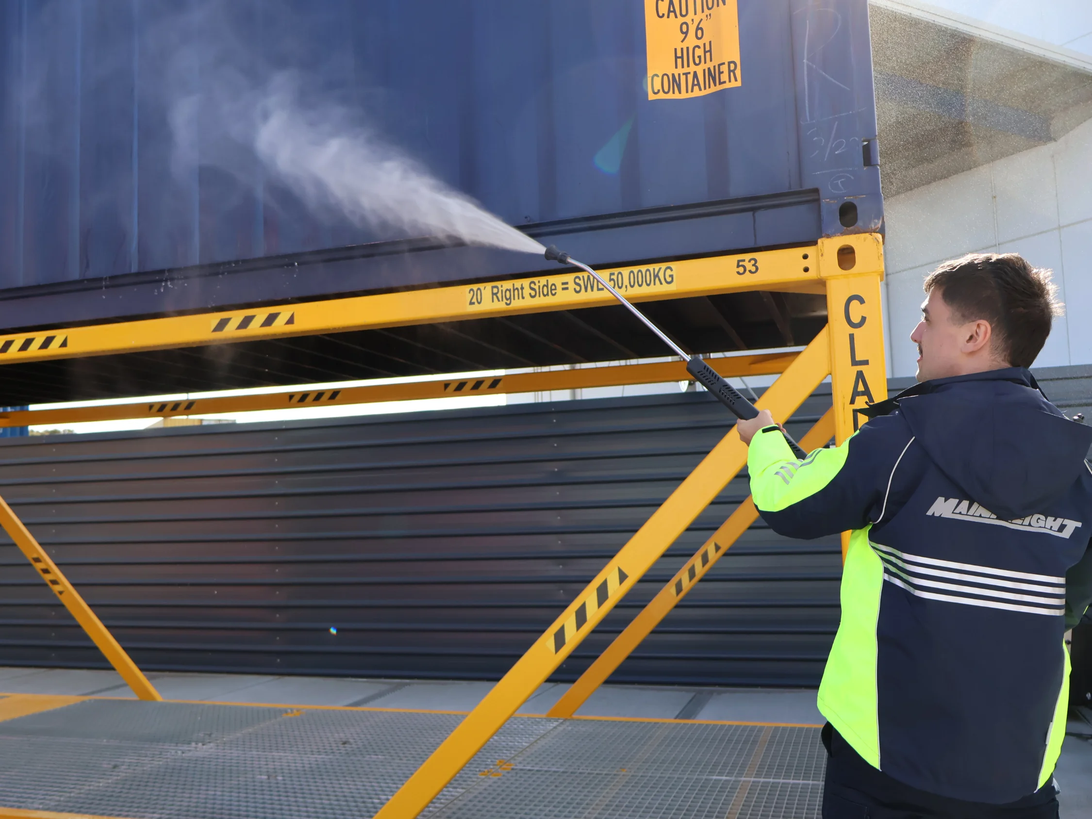 Team member washing down blue container after rural tailgate inspection 